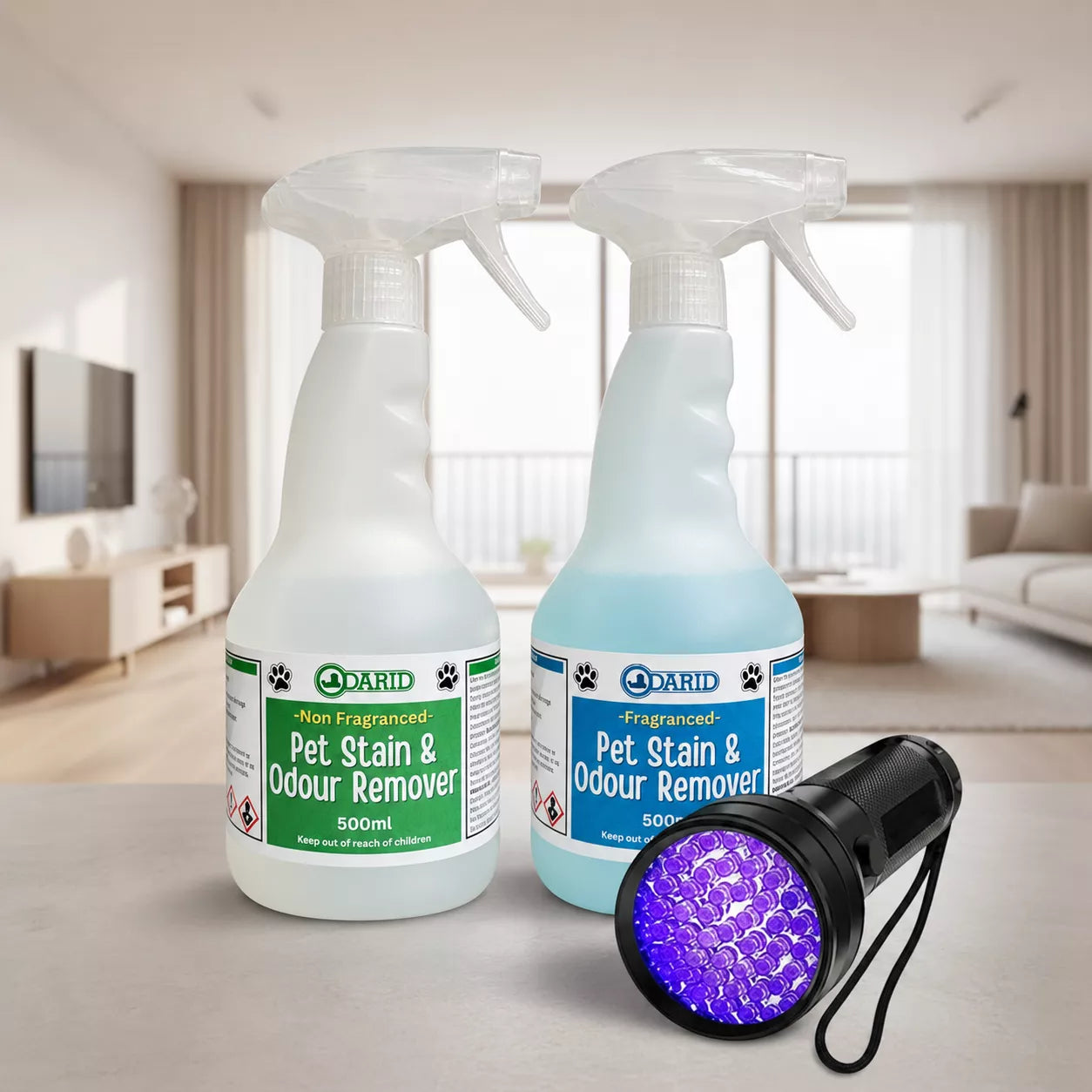 Two Odarid Pet Stain & Odour Remover spray bottles, one with green label and one with blue label, displayed alongside a black 51 LED UV flashlight on a light gray countertop with a blurred living room background.
