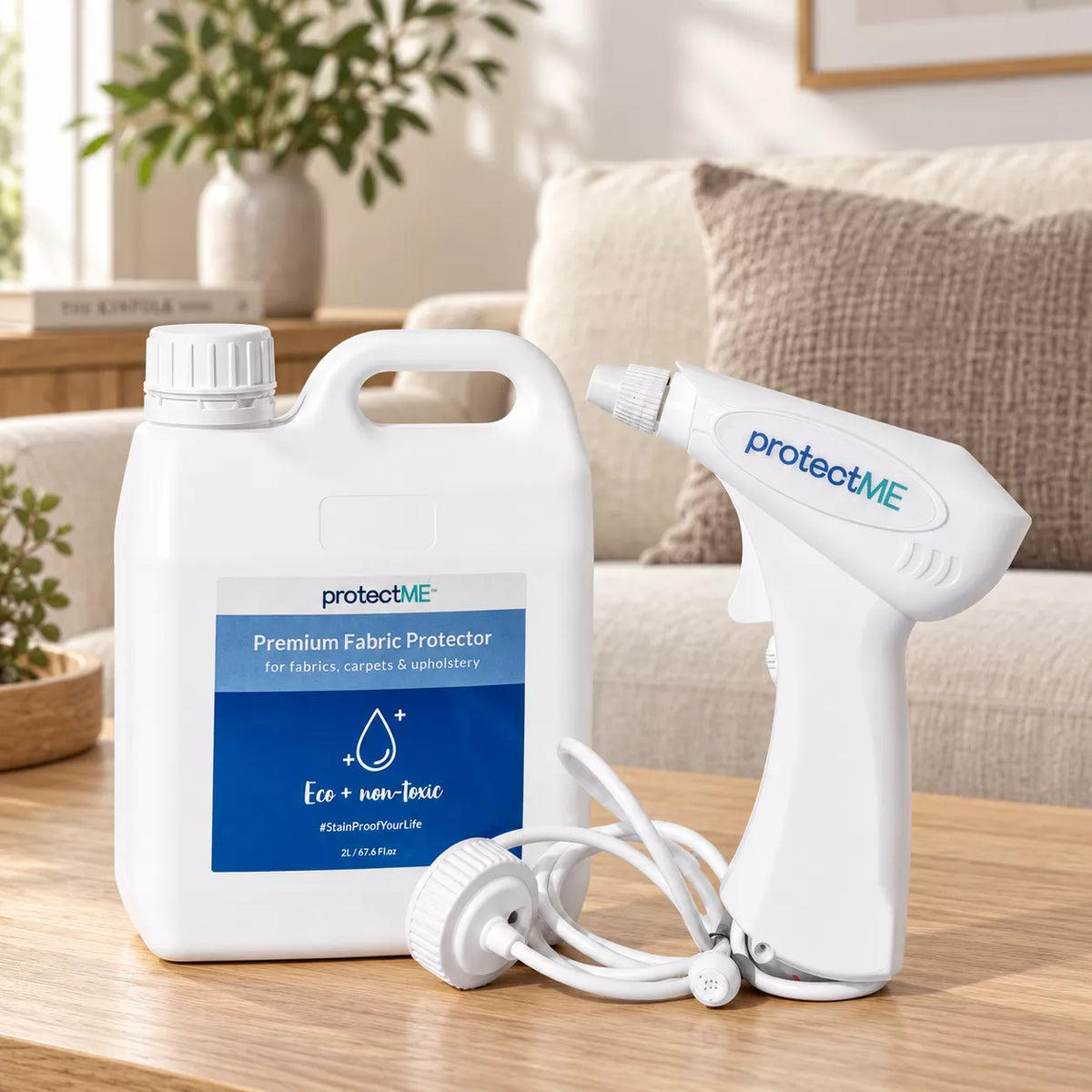 A Protect ME Premium Fabric Protector kit shown on a wooden table in a living room setting, featuring a large white plastic bottle with a blue label and a white handheld spray nozzle with a coiled white hose.